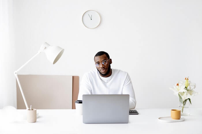 Black man looking at camera in front of laptop